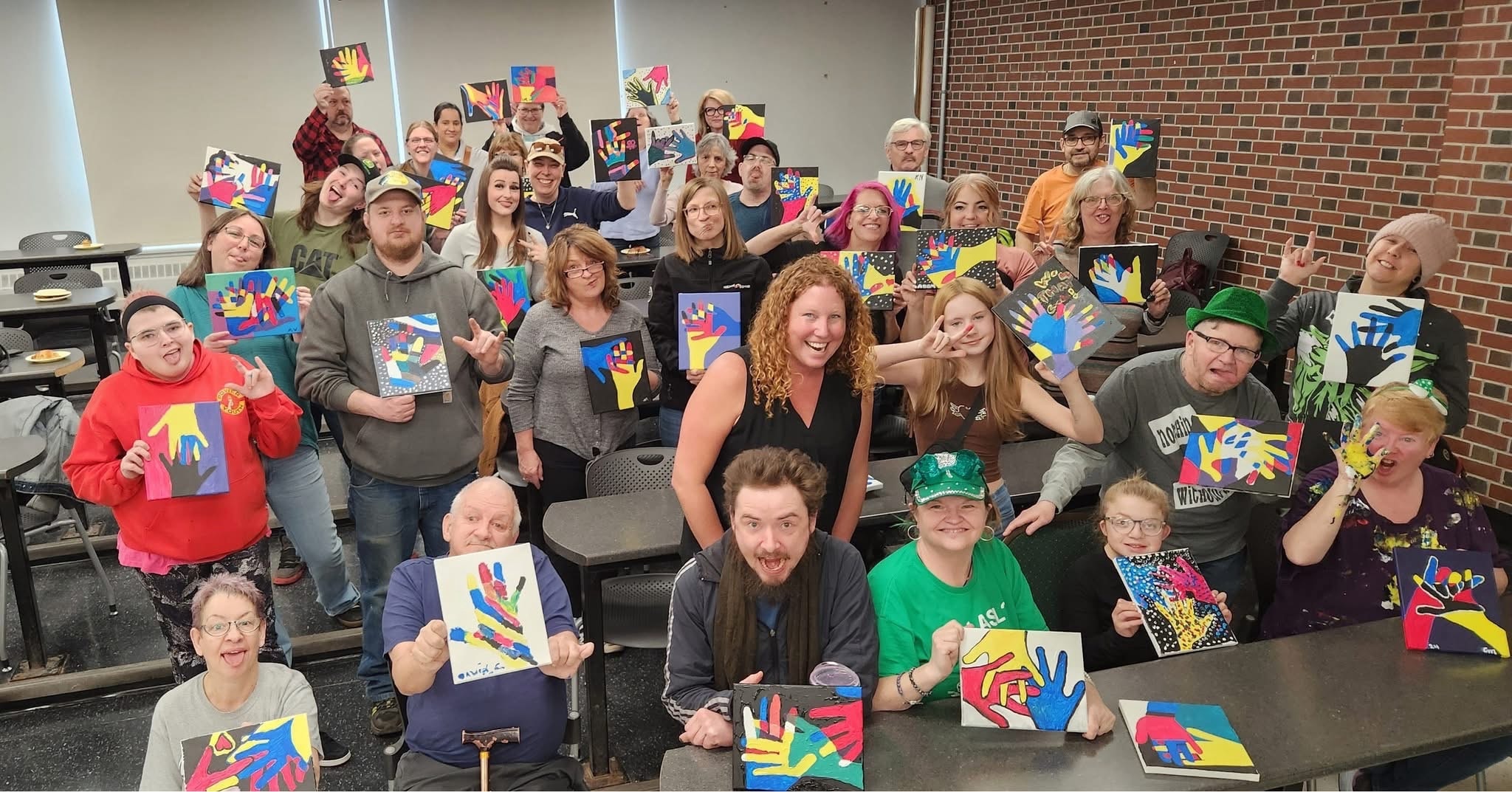 Community members proudly displaying colourful hand-print artwork at a creative workshop