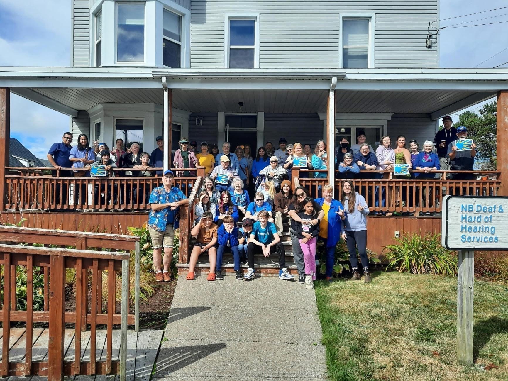 Large group gathered on the steps and porch of the NB Deaf and Hard of Hearing Services building